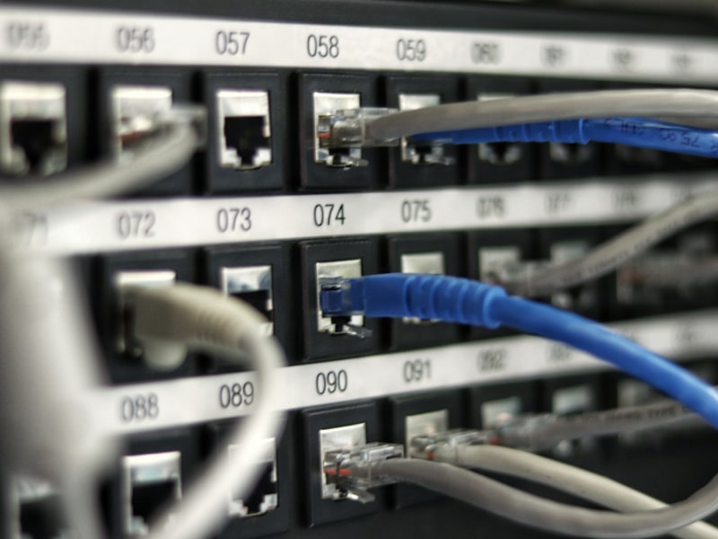 A network patch panel with numbered ports and blue ethernet cables plugged in.